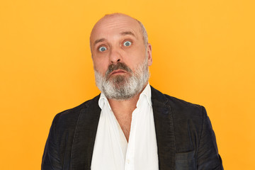 Portrait of bug eyed unshaven elderly male with expressive mimics, staring at camera in full...