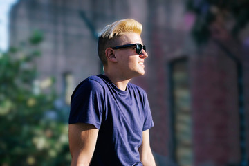 Fototapeta premium Young blond guy with sunglasses looking away outdoors in the city
