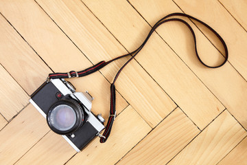 Old type reflex camera with strap on the floor