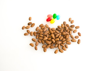 Smaller pinto beans close in on small group of different colored jelly beans. 