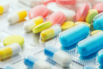 pile of medical pills  in red, blue and yellow colors in  silver plastic packaging