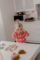 Little girl 2 years old sitting in the kitchen in red pajamas, messing with flour, baking...