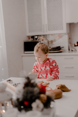 Little girl 2 years old sitting in the kitchen in red pajamas, messing with flour, baking...