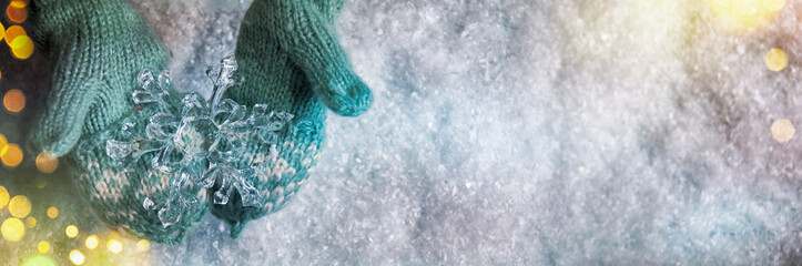 Winter snow background, kids hands holding christmas ornament