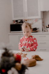 Little girl 2 years old sitting in the kitchen in red pajamas, messing with flour, baking...