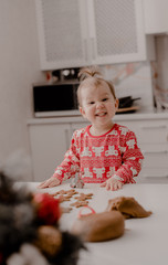 Little girl 2 years old sitting in the kitchen in red pajamas, messing with flour, baking...