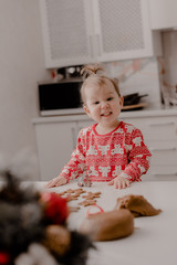 Little girl 2 years old sitting in the kitchen in red pajamas, messing with flour, baking...