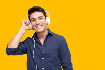 Young man listening music with headphones in playlist song application isolated on yellow background