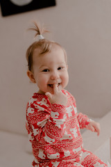 Little girl 2 years old sitting in the kitchen in red pajamas, messing with flour, baking...