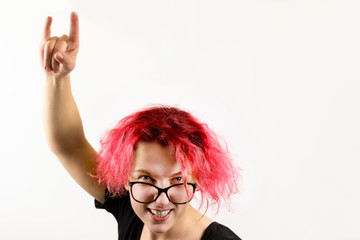 A girl rocker with red hair shows a hand gesture Heavy Metal HM on a white background. Concept of informal youth and heavy rock