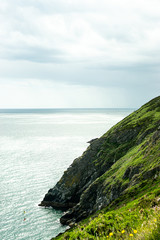 Photo of a green mountain next to the sea in Howth, Ireland