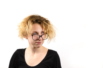 Close-up of a funny girl student in glasses with a strange hairstyle looks away, on a white background. Concept of emotions and youth