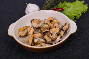 Pickled mussels in the bowl served pepper, garlic and salad
