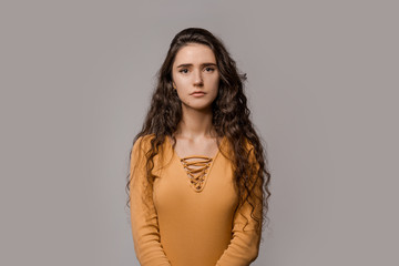 Fototapeta premium Sad offended young beautiful woman feels humiliated, moral abuse concept. People emotions, problems with communication. Over grey studio background