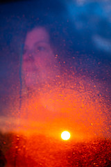 Lady look through a wet window a beautiful sunset after the rain.
