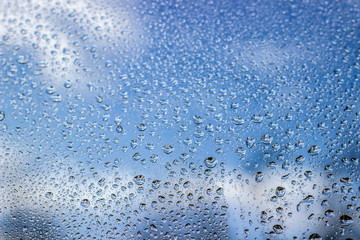 Rain drops on window glass on blue color..