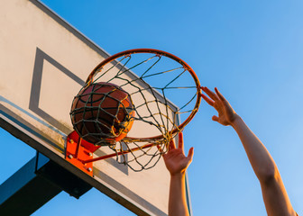 Street basketball slam dunk competition. Close up of ball falling into the hoop. Urban youth game....