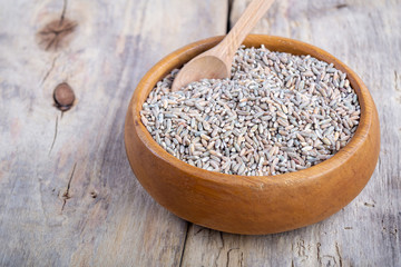 Unpeeled raw oats in a wooden plate on a wooden table