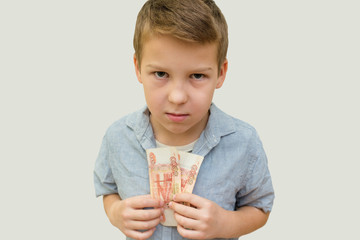 a schoolboy a boy of 10 years of Asian appearance holding in his hands banknotes of 5 thousand Russian rubles on an isolated background finance theme