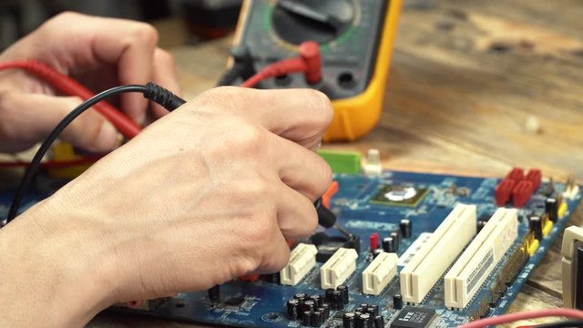 An engineer repairs a motherboard, he measures data with a multimeter.