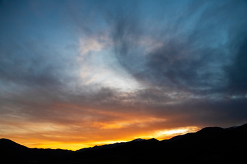 Beautiful bright sunset sky over the mountains silhouette . Dramatic colorful clouds after sunset. Nature backgrounds.