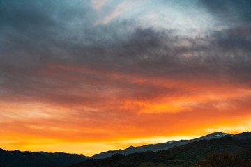 Beautiful bright sunset sky over the mountains silhouette . Dramatic colorful clouds after sunset. Nature backgrounds.