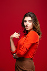 Young girl student or business woman girl with skeptic expression took off glasses on a red background.