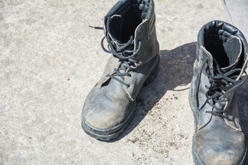 Old Black Leather army boots. Military boots of soldiers standing on the cement ground.