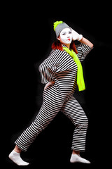 Portrait of female mime artist, isolated on black background. Young woman in striped suit and...