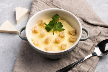 Cheese cream soup with croutons and parsley on gray marble stone table. Flat lay, top view and copy space for your text