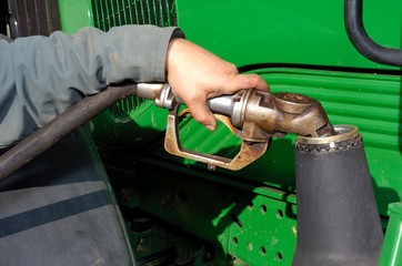Agriculteur effectuant le plein de gas-oil GNR pour son tracteur. Main tenant le pistolet
