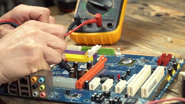 An engineer repairs a motherboard, he measures data with a multimeter.