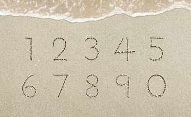 Alphabet letters handwritten in the sand on the beach
