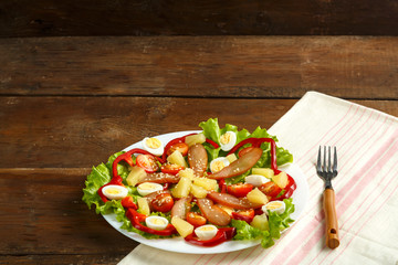 Pan-Asian salad with chicken and pineapple in a plate on a wooden table on a napkin.