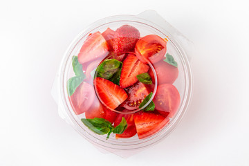 Salad in plastic package for take away or food delivery isolated on a white background. Nutritional Diet Snack with strawberries and basil