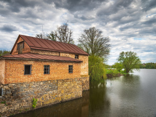 Fototapeta na wymiar building of old water mill on the river in spring cloudy day in Ukraine