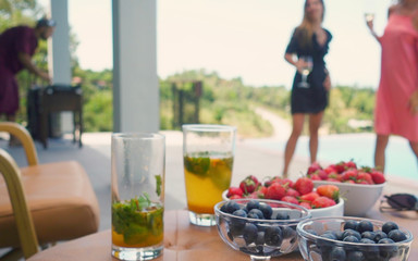  Blurred party background with dancing people dj and drinks berryies on table