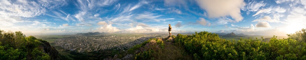 Fototapeta premium The climber is standing on top of a high mountain in the background of a stunning landscape and sunset. Mauritius Island, panorama