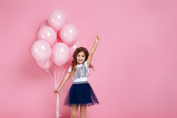 Fototapeta na wymiar Smiling adorable little child girl posing with pastel pink air balloons isolated over pink background. Beautiful happy kid on a birthday party. copy space