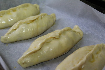 semi-finished products, pies with filling are on baking paper in the oven