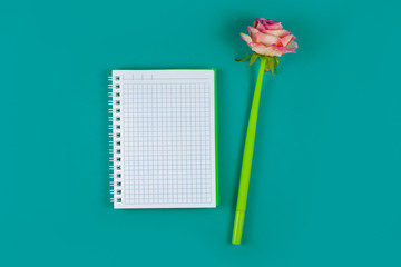 Notepad and pen in the shape of a flower on an azure background. Top view.