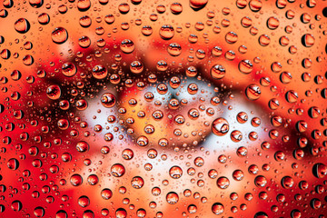 Female eye through drops of water on glass