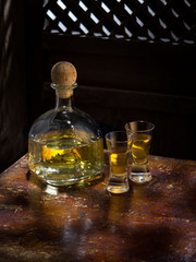 Close up view of bottle of tequila anejo and glasses on color background