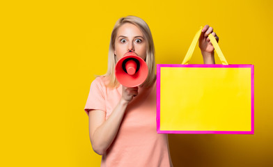 Blonde girl in pink dress with shopping bags and megaphone
