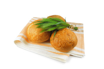 Freshly baked wheat bread on linen napkin with bunch of field spikelets isolated on white background    