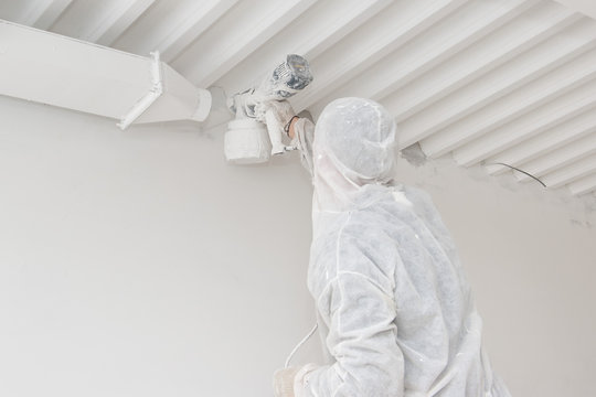 Painter in white clothes paints white walls.