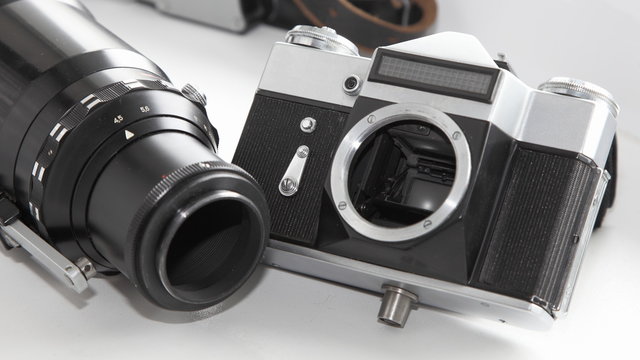 Old photoghraphic equipment - retro SRL film camera and big telephoto lens  closeup