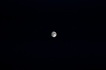 Almost full moon in the center of the black night sky. Astronomy.