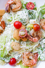 Caesar salad with tuna and shrimp on a white plate