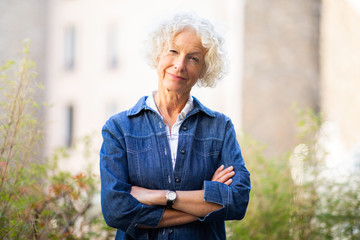 attractive older woman posing outside with arms crossed